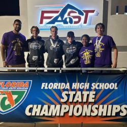State swim and dive competitors with coaches at FHSAA State Championship banner